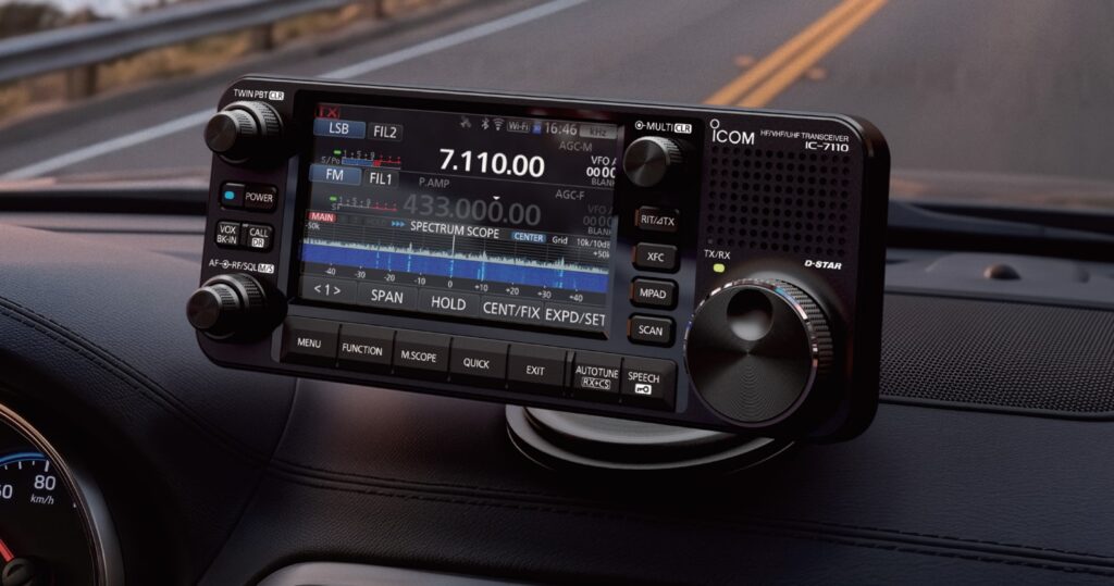 Ovládacia hlavica Icom IC-7110 na palubnej doske vozidla, s dvomi zobrazenými pásmami VFO A (7.110,00 kHz LSB) a VFO B (433.000,00 kHz FM), spektroskopom v reálnom čase a ikonami WiFi a Bluetooth na displeji